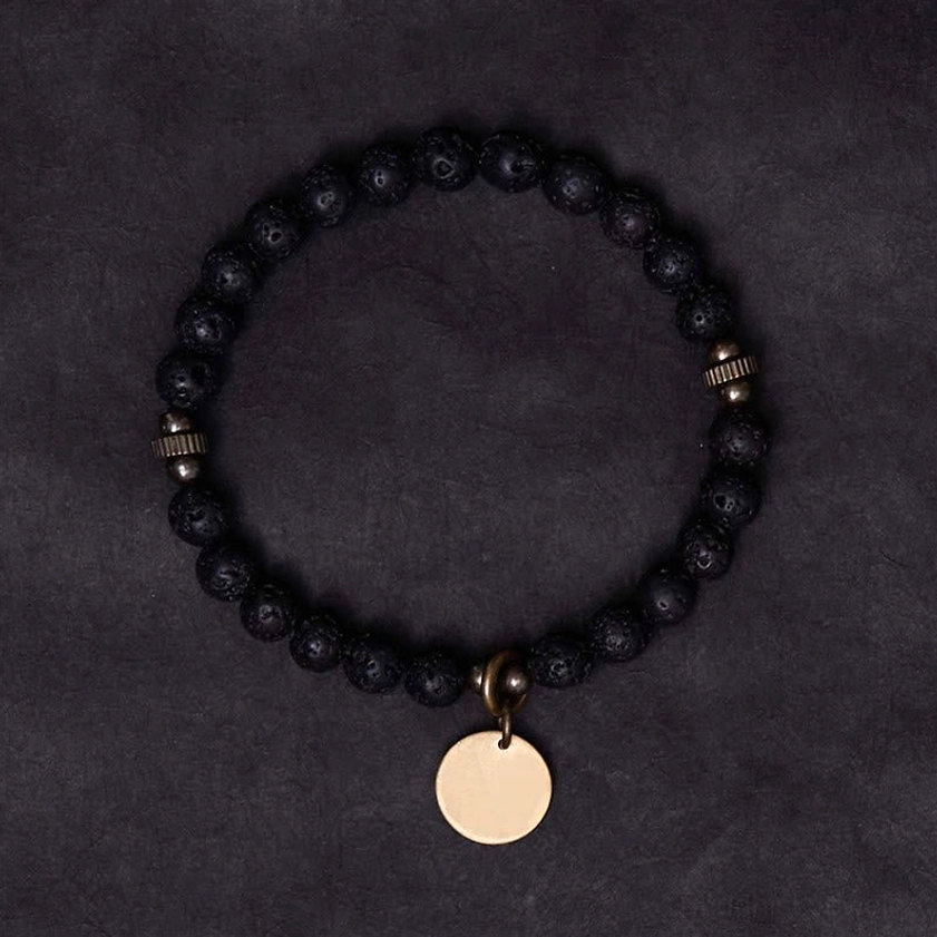 Lava rock Buddhist healing bracelet flat lay top-down view, displaying full circular design with antique bronze clasp and round disc pendant charm