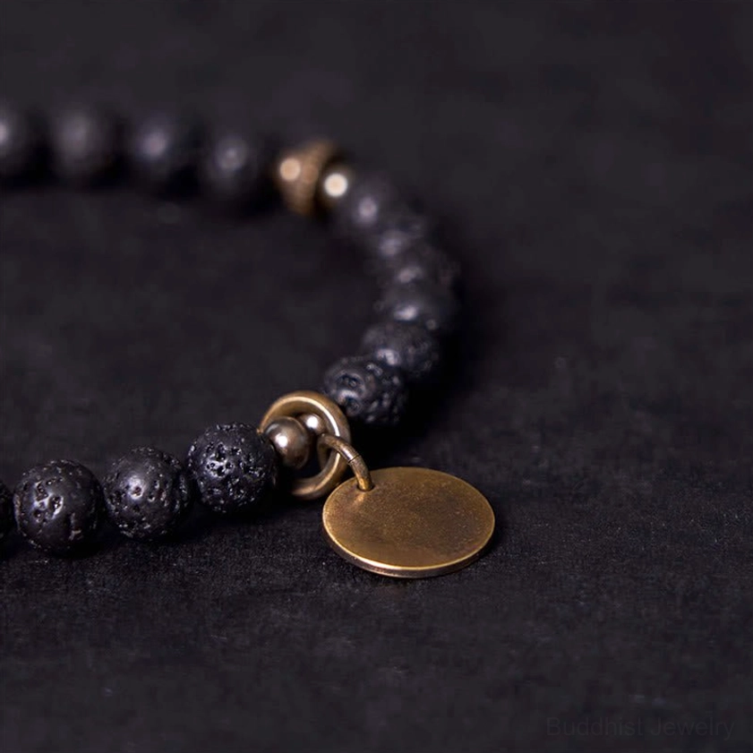 Close-up detail of lava rock beads bracelet clasp and copper pendant, highlighting rough porous black bead texture and antique bronze toggle clasp