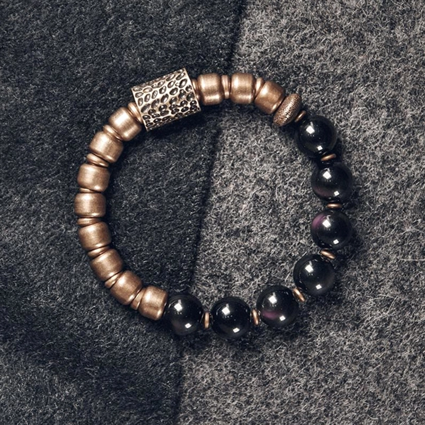 Lava rock healing bracelet with brass accents displayed on dark surface, showing complete bead arrangement