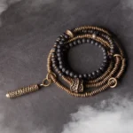 Vintage lava rock and brass multilayered healing bracelet set with tassel charm - top-down flat lay view