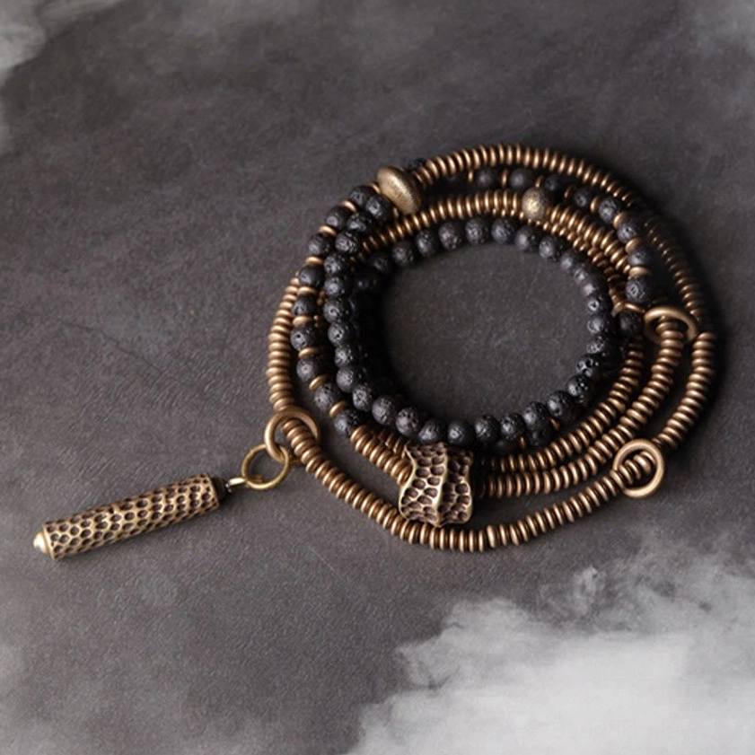 Vintage lava rock and brass multilayered healing bracelet set with tassel charm - top-down flat lay view