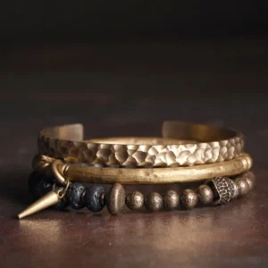 Lava rock copper balance cuff bracelet stacked set with beaded strand and brass accents on dark background