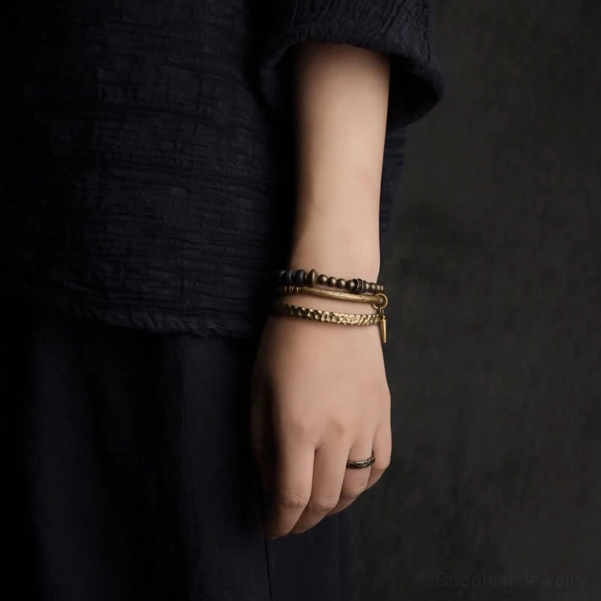 Layered lava rock and copper balance bracelet set worn on wrist displaying stacked cuffs and beaded strands