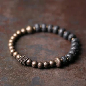Lava rock and copper beaded Buddhist bracelet with black porous beads and bronze metal accents on rustic brown surface