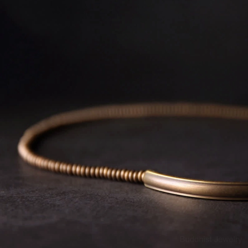 Antique copper bead necklace with lava rock flat lay showing smooth brass chain and curved metal tube details on dark tabletop