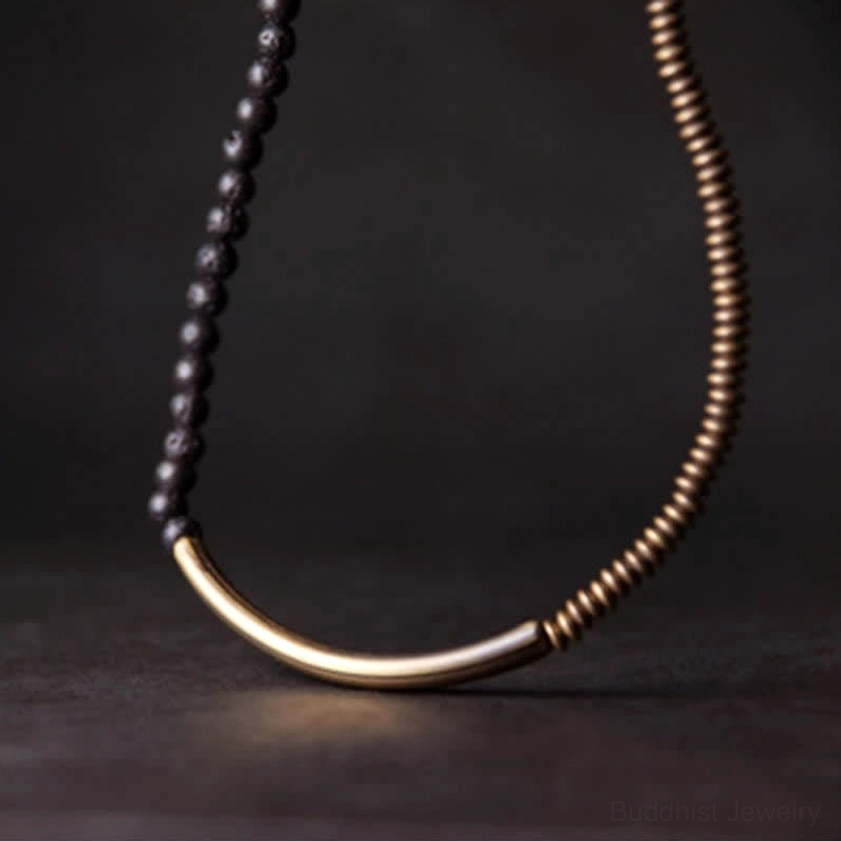 Long single chain lava rock copper necklace with black volcanic beads and antique brass metal flat lay on gray background