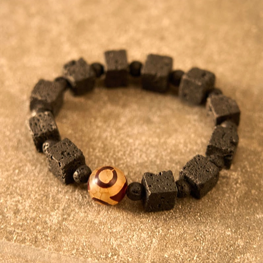 Full flat lay display of handcrafted lava rock and dzi bead protection bracelet on neutral matte background