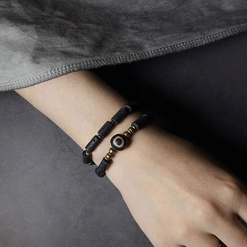 Slim single-wrap lava rock Dzi bead bracelet side view with three-eyed focal bead
