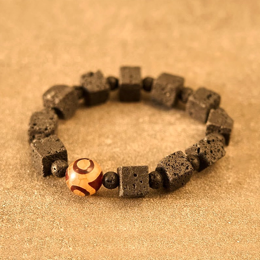 Lava rock and dzi bead healing bracelet with warm-toned volcanic stone beads displayed on tan surface