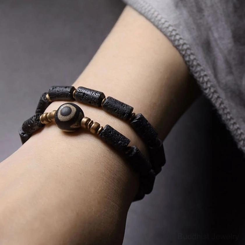 Layered lava rock three-eye Dzi bead wrap bracelet worn on human wrist showing fit