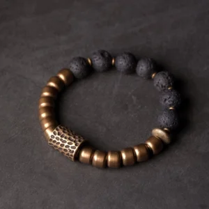 Lava rock and brass healing bracelet with rainbow obsidian beads, top-down full view on dark background showing complete bead arrangement