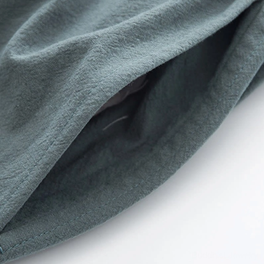 Light cyan stand collar tang shirt hanging display showing traditional frog button craftsmanship and linen quality