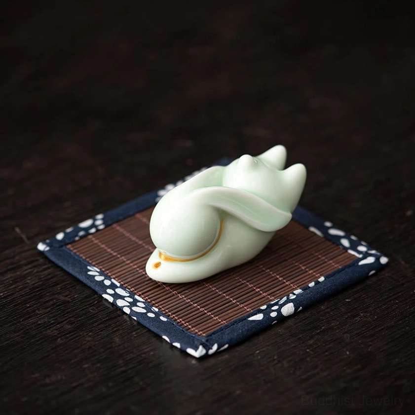 Light green ceramic rabbit ornament with smooth glazed surface on blue floral bamboo mat dark wood desk