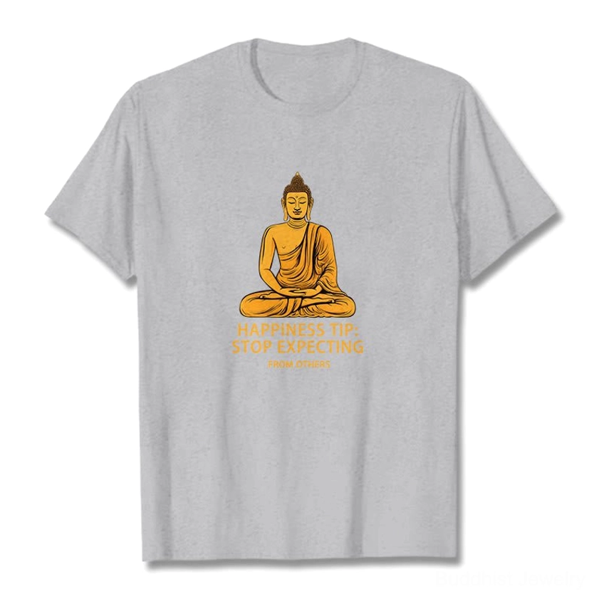 Light grey Buddhist mindfulness graphic t-shirt with golden seated Buddha and 'Stop Expecting From Others' text, front flat lay