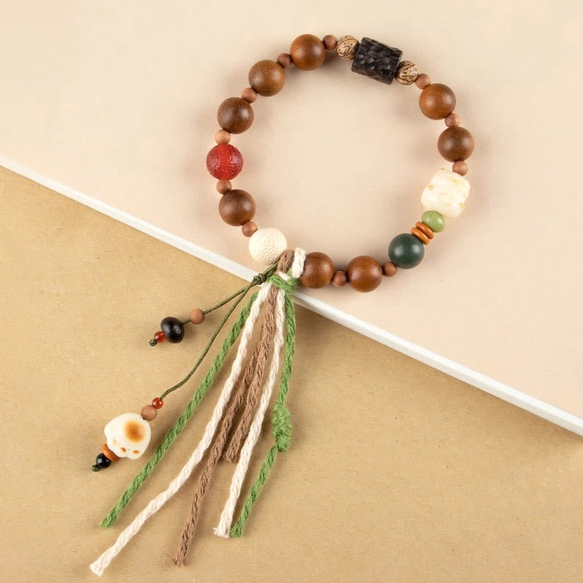 Lightning strike wood bodhi seed bracelet with cat paw charm and handwoven cotton tassel, top angled view showing mixed colored beads