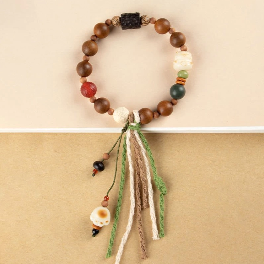 Top-down view of lightning strike wood bodhi bracelet with cat paw pendant on beige tabletop, consistent design showcase