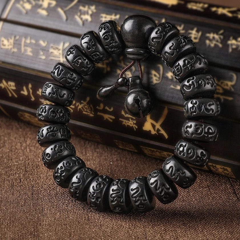 Lightning Strike Wood Buddhist protection bracelet with carved Om Mani Padme Hum mantra beads, flat lay on vintage calligraphy scroll background