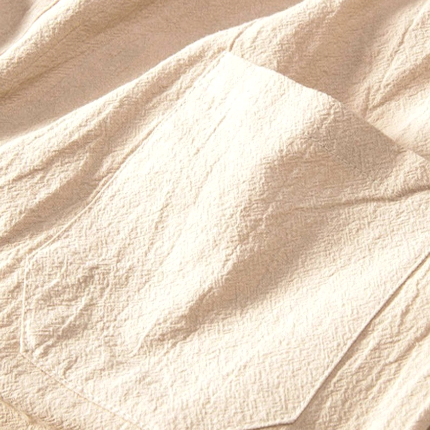 Patch pocket design detail on beige crinkled linen pants - functional and traditional Buddhist-inspired styling