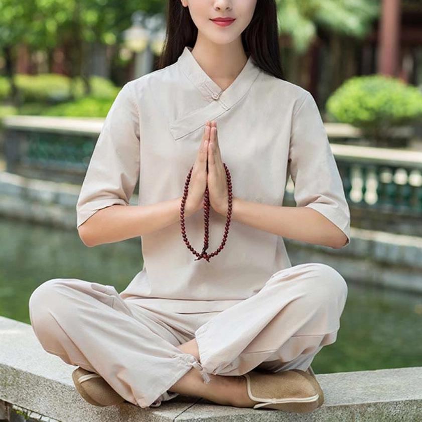 Light khaki linen meditation and tai chi two-piece set with V-neck top and relaxed pants, flat lay view in traditional garden setting