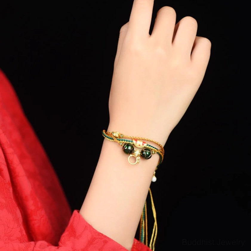 On-wrist display of multi-strand liuli glass bead bracelet with dark green glass beads and hanging tassel, worn styling