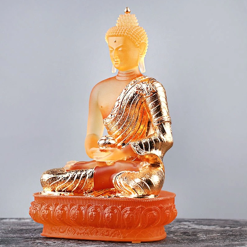 Left side three-quarter view of amber Liuli glass Buddha in cross-legged meditation pose on lotus base