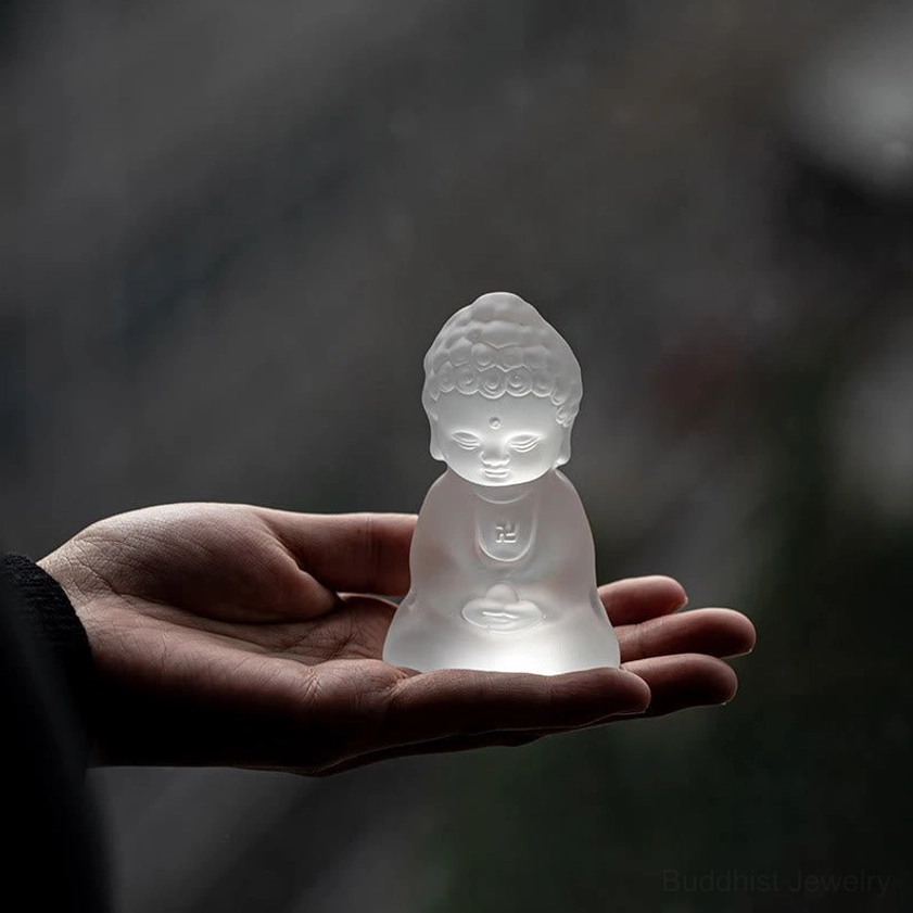 Tiny Liuli Buddha statue held in palm showing compact size and frosted glass craftsmanship