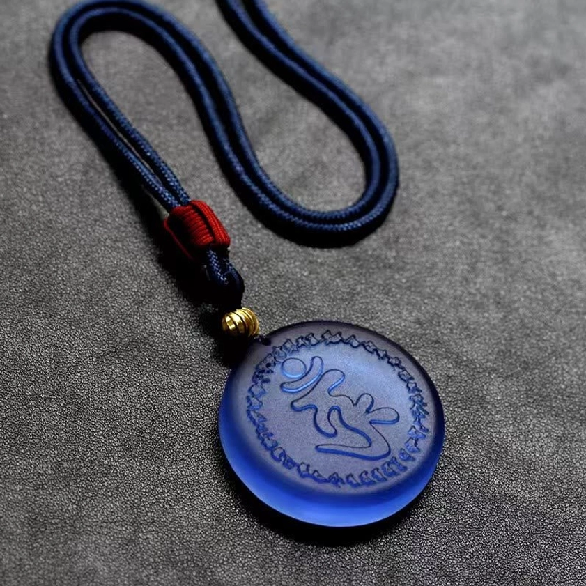 Blue Liuli crystal Shurangama Mantra pendant with engraved characters and decorative border close-up