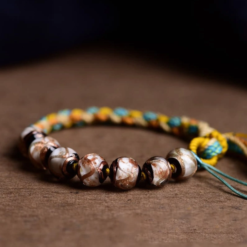 Close-up detail of woven rope and patterned glass beads showing bracelet weave structure