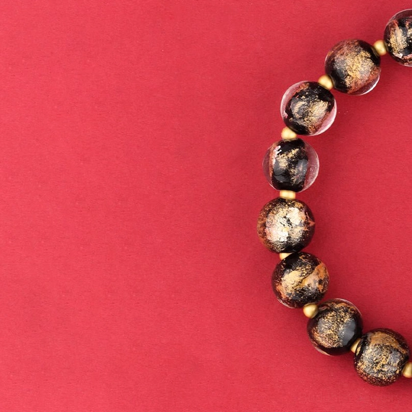 Side angle detail view of incense ash glass beads showing texture and speckled finish of Buddhist spiritual bracelet