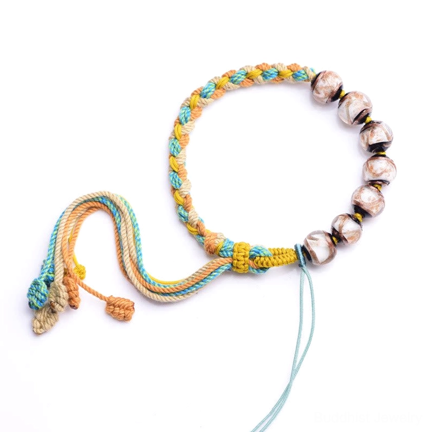 Handmade cotton rope Buddhist bracelet with brown glass beads and adjustable drawcord on white background