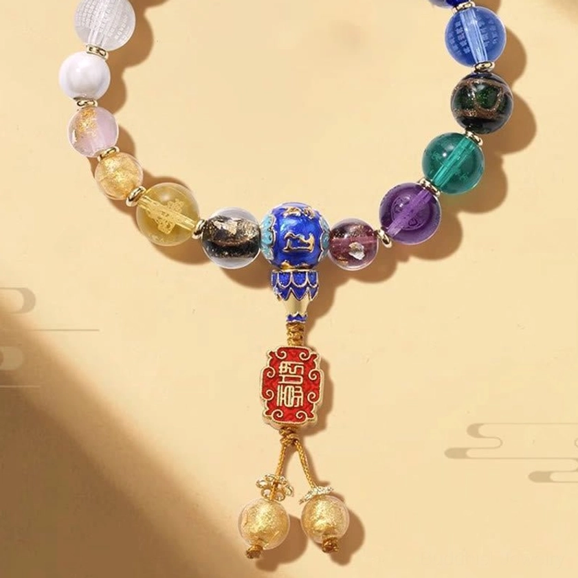 Multi-color incense ash liuli glass mala bracelet close-up showing gradient and solid hue beads with enamel charm and golden tassel bells