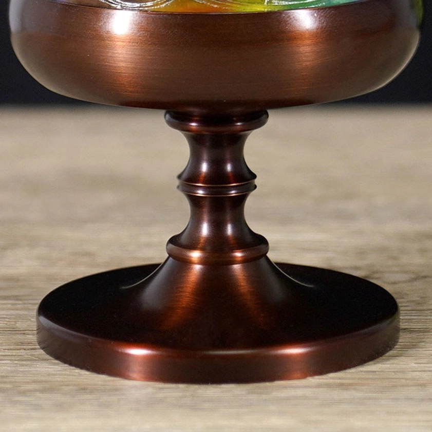 Close-up of polished bronze metal pedestal base with turned spindle and wide round foundation
