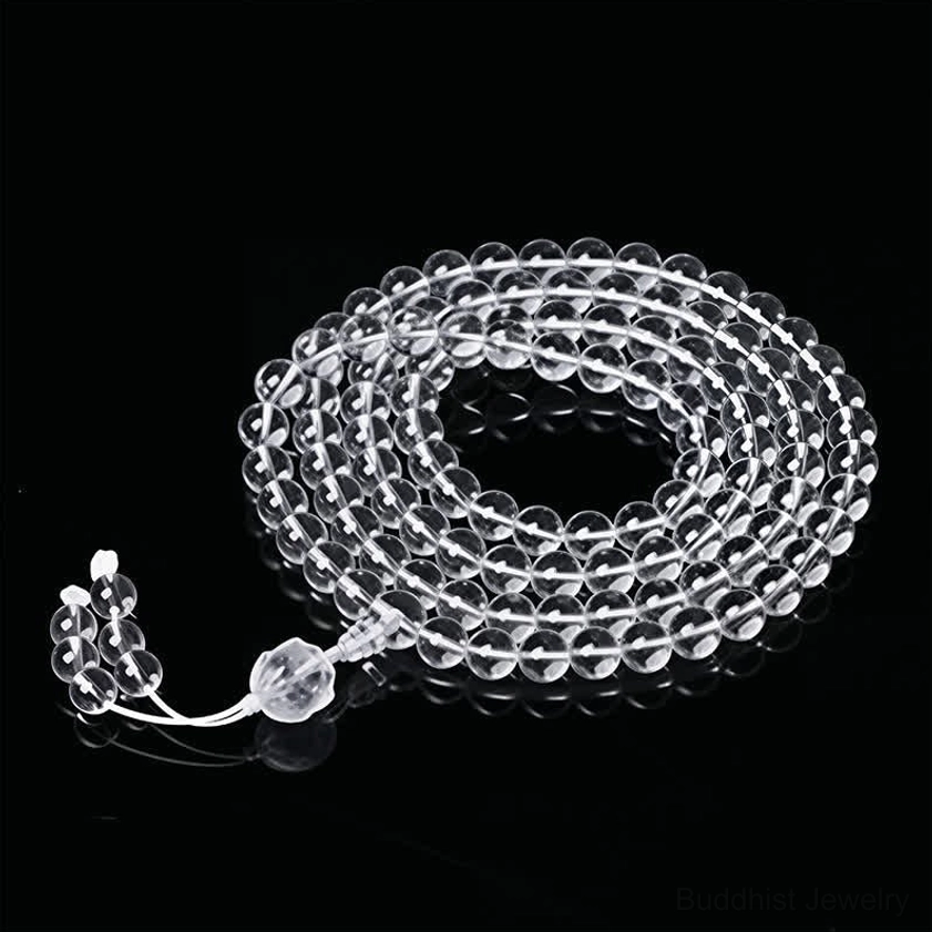 White string 108 bead Buddhist prayer mala with clear liuli beads and crystal tassel, flat lay studio view