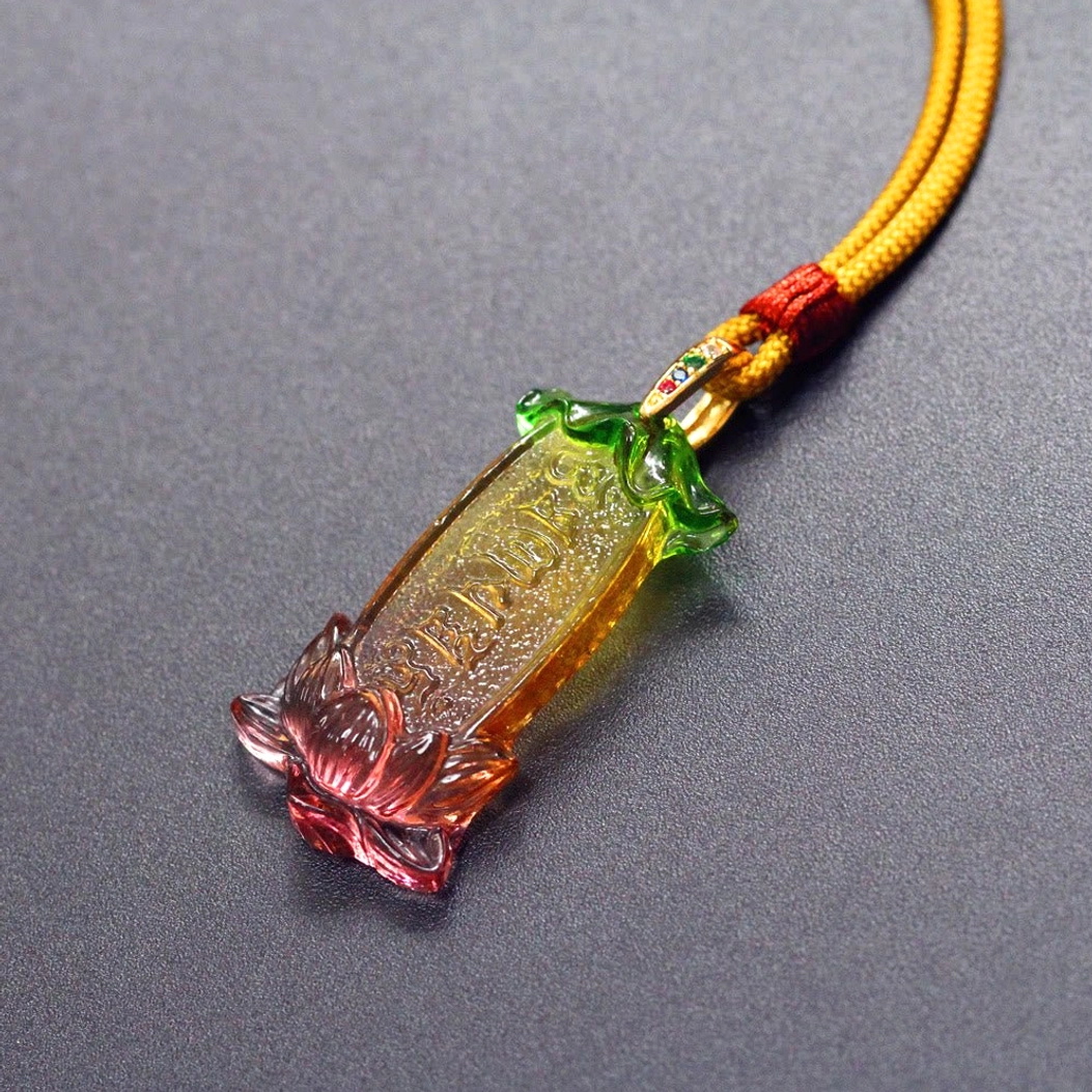 Buddhist Liuli lotus necklace detail showing metal-decorated clasp and red decorative rope knot, three-quarter overhead angle