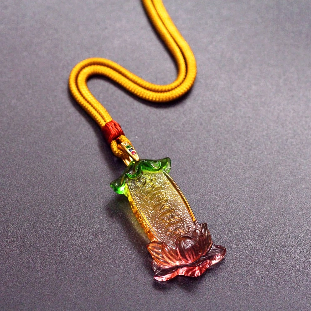 Om Mani Padme Hum Liuli pendant hanging on yellow braided cord, side profile view showing mantra engraving