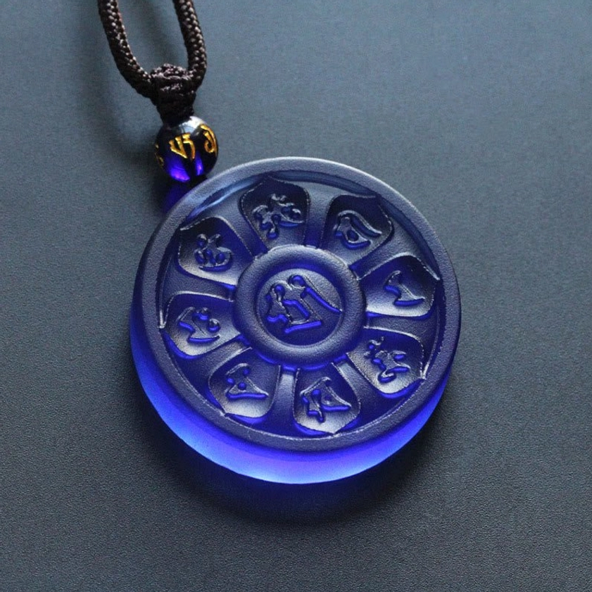 Close-up of matte translucent blue Liuli pendant showing clear carved mantras and natural cotton cord