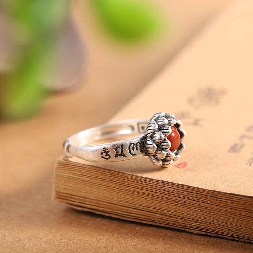 Lotus red agate sterling silver ring oblique view on book edge with visible gemstone and engraved sutra