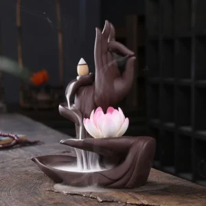 Buddhist lotus backflow incense burner with buddha hand ceramic design, displaying cascading aromatic smoke effect on wooden table