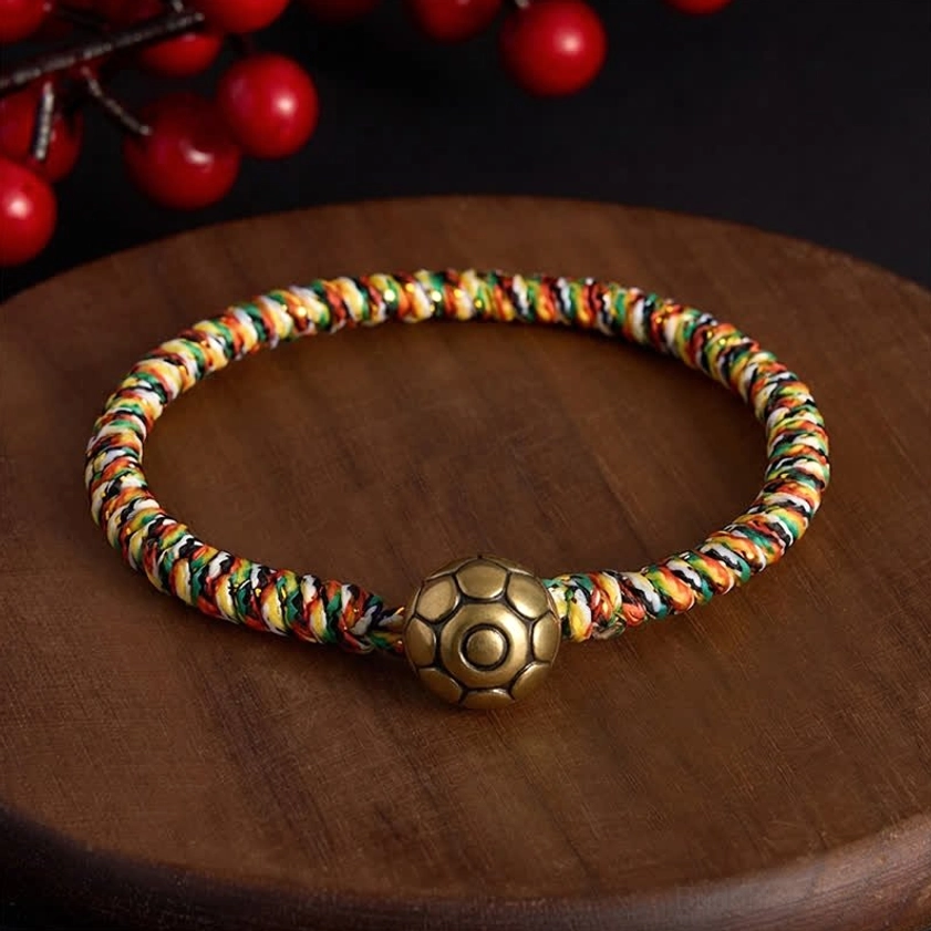 Handwoven lotus balance bracelet with copper bagua charm on natural wood surface with festive decor