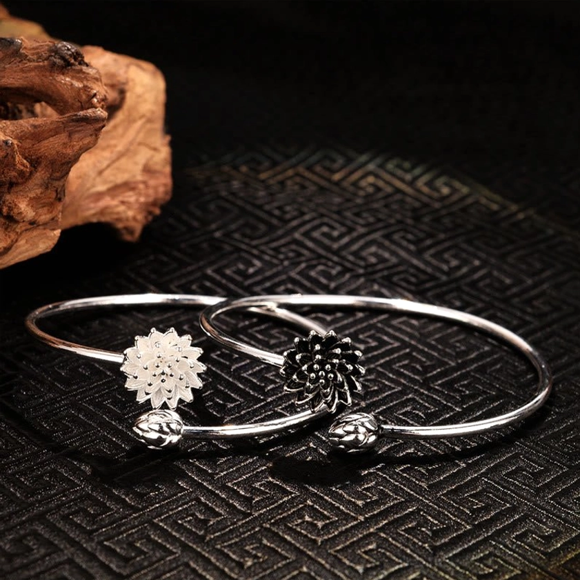 Pair of lotus bangles - white and dark varieties with bud accents, flat lay top-down composition