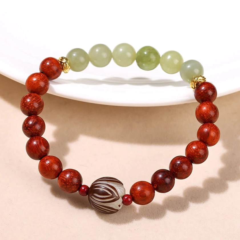 Flat lay view of handmade Buddhist bracelet featuring 8mm rosewood and jade beads with carved 12mm lotus Bodhi seed on white ceramic plate