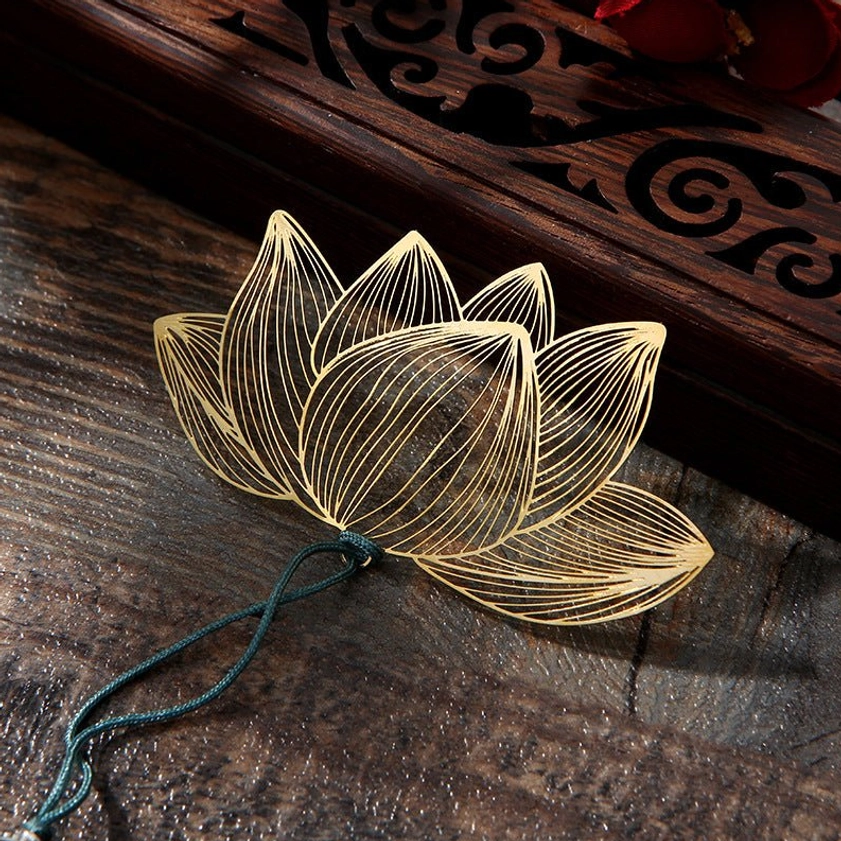 Close-up detail of hollow lotus bookmark charm - fine line carving texture in brass material with teal hanging cord