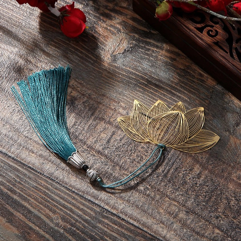 Lotus metal bookmark set flat lay - separate gold lotus charm and decorative teal tassel on rustic wooden surface