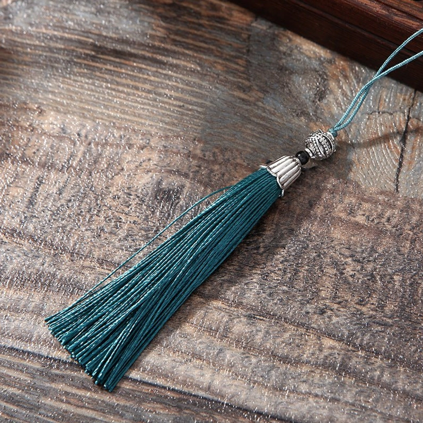 Lotus bookmark teal tassel accessory - side view showing silver beaded decorative trim on vintage wooden table