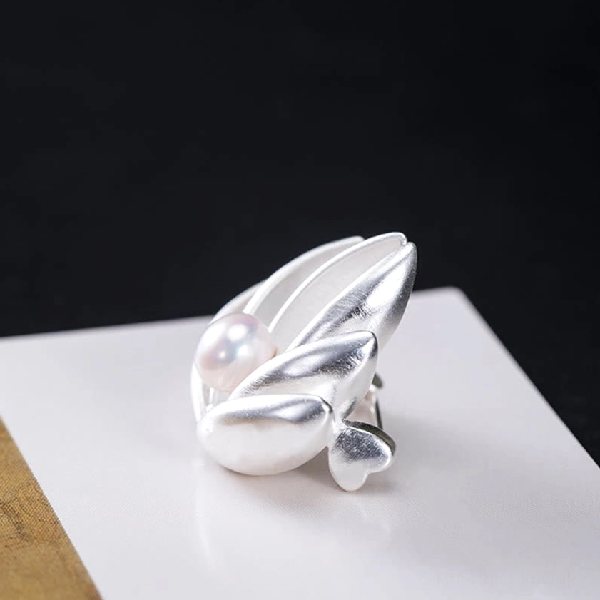 Side profile of sterling silver lotus brooch displaying three-dimensional layered petal depth and pearl placement