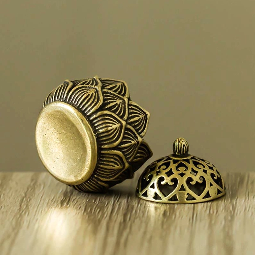 Low angle side view showing the textured lotus petal base and hollow carved lid of the copper incense burner