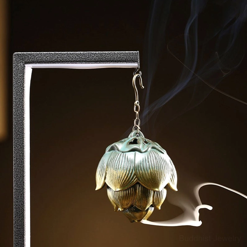 Hanging lotus incense burner with petal texture and gold trim emitting fragrant smoke, front low angle view with metal frame backdrop