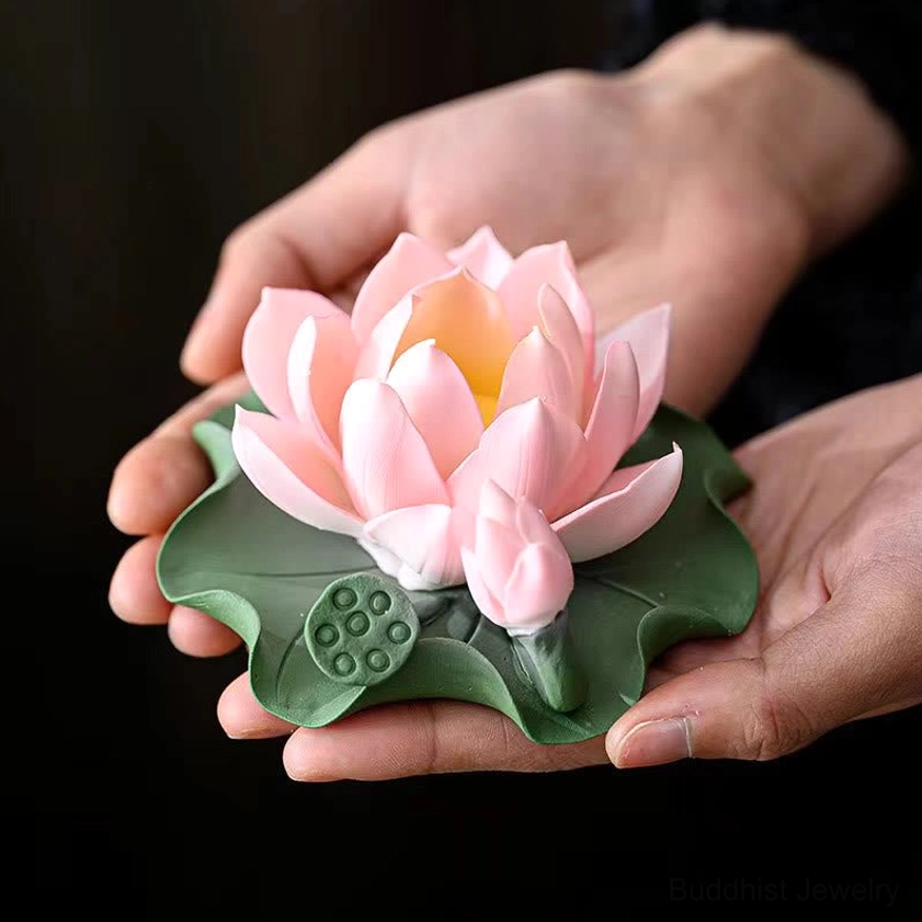Hand holding artisan lotus ceramic incense burner showing light pink bloom and leaf base