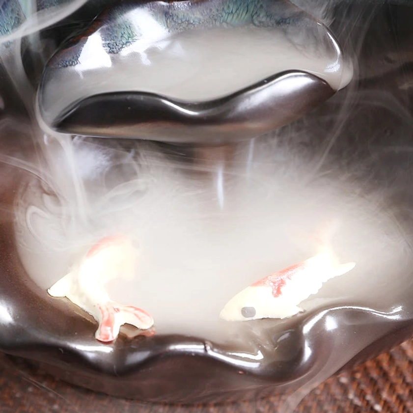 Top-down close-up view of ceramic lotus incense burner tray showing koi fish decorations and backflow smoke collection detail