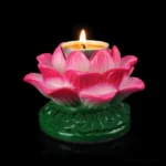 Single lotus ceramic candle holder with lit tealight in pink gradient finish, green carved base, front top close-up view on black studio background